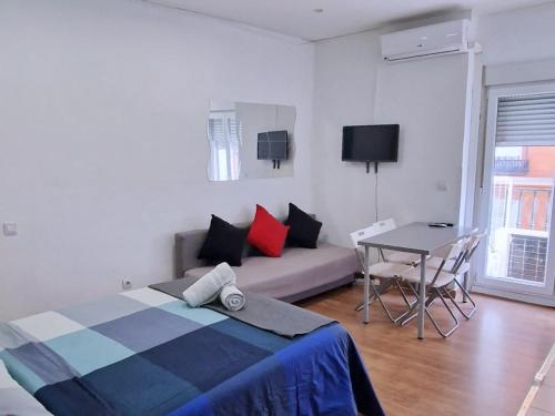 马德里Apartamentos EconoStay Barbieri 1的一间卧室配有一张床、一张桌子和一张沙发