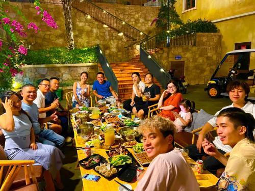 富国Sunset Hotel Phu Quoc - welcome to a mixing world of friends的一群人坐在一张长桌旁