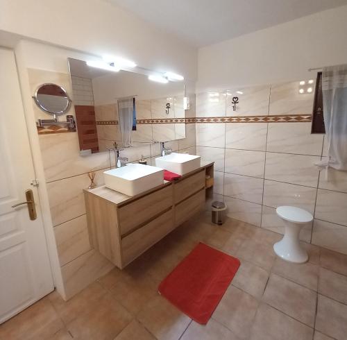 勒米伊巴斯蒂德·奥利维尔酒店的浴室设有两个盥洗盆和红色地毯。