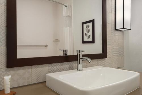俄克拉何马城Country Inn & Suites by Radisson, Oklahoma City - Bricktown, OK的浴室设有白色水槽和镜子
