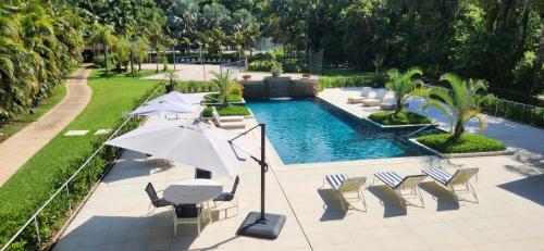 塞拉内格拉Radio Hotel Resort & Convention的游泳池设有椅子、遮阳伞和桌椅
