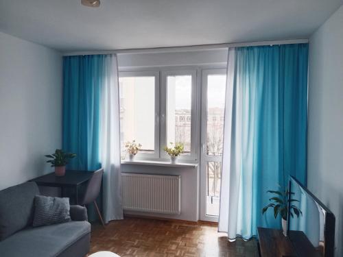 格涅兹诺Mieszkanie Turkus w Gnieźnie的客厅配有蓝色窗帘、沙发和窗户