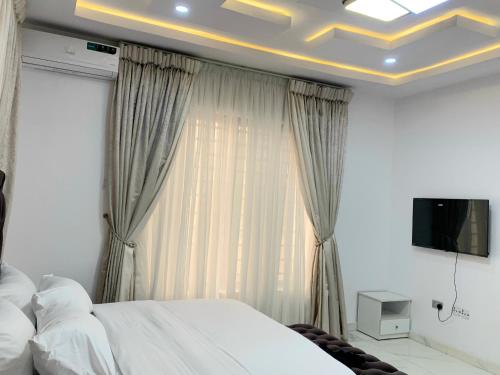 拉各斯The Residenze Adeniyi Jone Ikeja的一间卧室设有一张床,天花板上配有电视