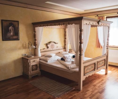 莫尔Hétkúti Wellness Hotel的一间卧室配有天蓬床和床头柜