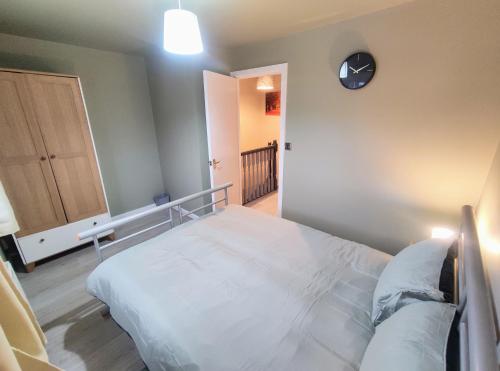 IdleHigh Rigg House Bradford - Luxury Accomodation with Private Parking的卧室配有一张床,墙上挂着一个钟