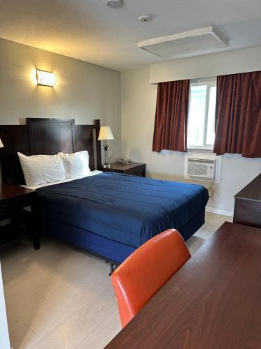 兰利Travelodge by Wyndham Langley的一间酒店客房,配有一张蓝色的床和一张书桌