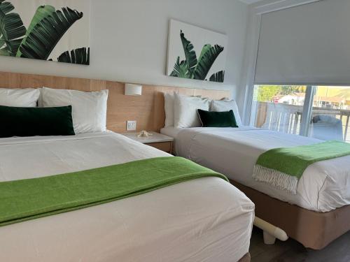 基拉戈吉尔伯特度假酒店的一间卧室设有两张带绿床单的床和窗户。