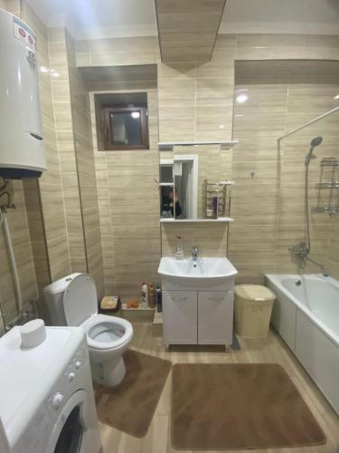 比什凯克Kojomkul的浴室配有卫生间、盥洗盆和洗衣机。