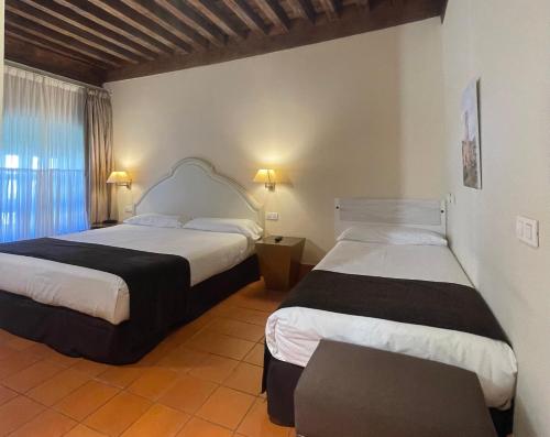 塞哥维亚圣安托尼奥皇家酒店的一间卧室设有两张床和窗户。