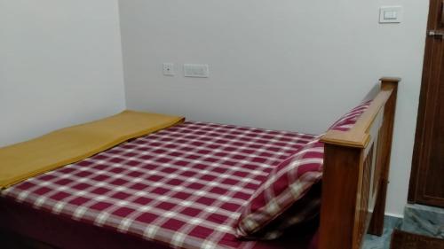 AntarasanteArasu Homestay的床上有红白的毯子