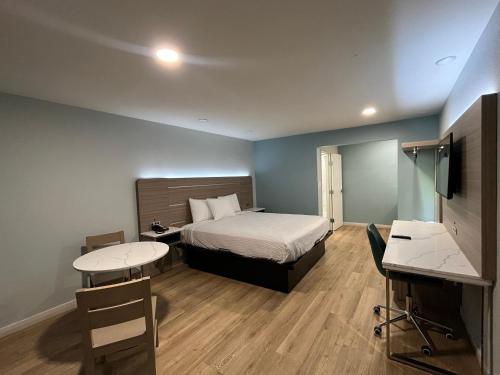 波莫纳Travelodge by Wyndham Fairplex Pomona的一间卧室配有一张床、两张桌子和一张书桌