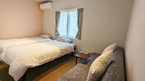 宫古岛MAHHO TERRACE MIYAKO的客房设有两张床、一张沙发和一个窗口。