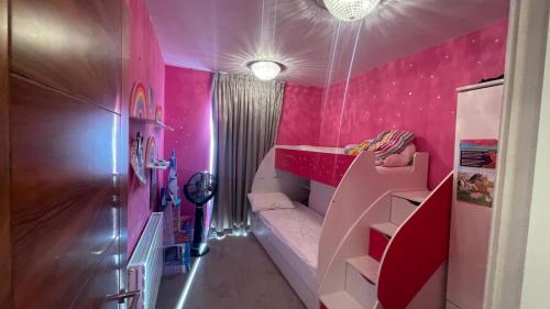 伦敦Modern and Unique Home in London, Chiswick的小房间设有粉红色的墙壁和一张双层床。