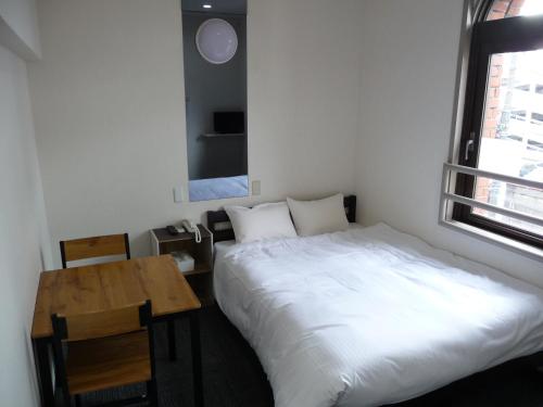 仓敷仓敷全球酒店 的一间卧室配有一张床、一张桌子和一个窗户。