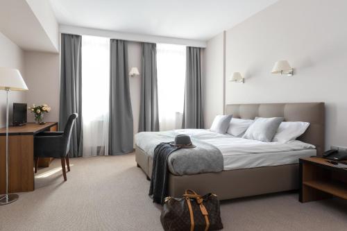 克拉科夫Grottger Luxury Boutique Hotel City的配有一张床和一张书桌的酒店客房