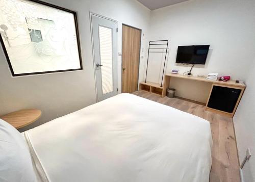台南燕宾大旅社的卧室配有白色的床和电视。