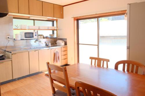 四万十市四万十川傍にある日本家屋まるごと「貸切宿　ほとり」的一间带木桌的厨房和一间餐厅