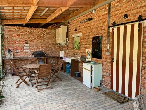 GeetbetsHoeve Hulsbeek: genieten van de natuur en de rust的室外厨房配有桌椅和砖墙