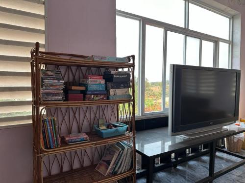 贡布The Vibe Guesthouse的客厅配有电视和带书籍的书架。