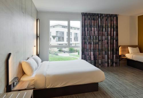 RocquencourtB&B HOTEL Versailles Rocquencourt的酒店客房设有床和窗户。