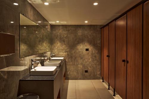 范兰德凡Triptam Vrindavan的浴室设有3个水槽和一排镜子
