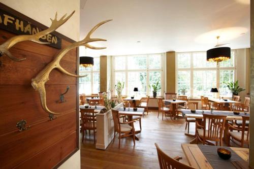 科尔斯万特牧歌沃尔加斯特斯酒店的餐厅设有桌椅,墙上装饰有鹿角。