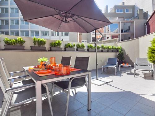 巴塞罗那帕拉勒怡人套房酒店的阳台配有桌椅和遮阳伞