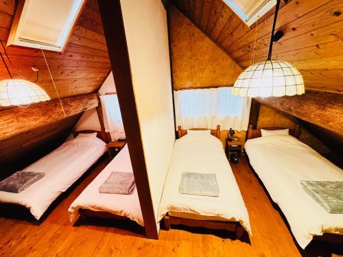 由布市Yufuin Log House no Yado Tom Sawyer的木墙客房的两张床
