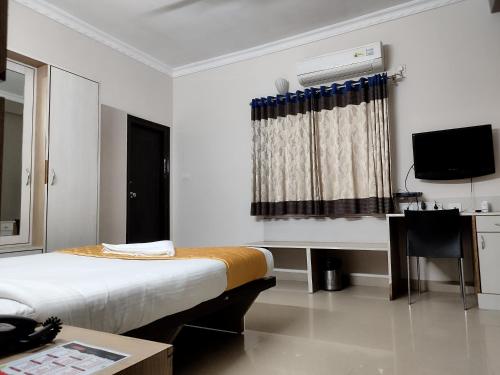 海得拉巴Luxor Park Service Apartment的一间卧室配有一张床、一张书桌和一台电视