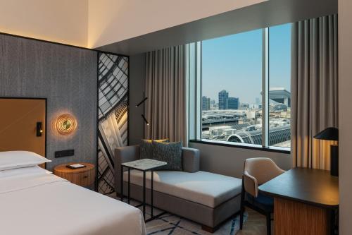 迪拜迪拜阿联酋购物中心喜来登酒店的配有一张床、一张书桌和一扇窗户的酒店客房