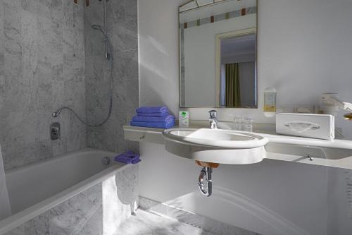 黑灵斯多夫芮斯登兹酒店的一间带水槽、浴缸和镜子的浴室