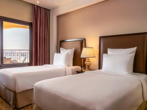 拉斯阿尔卡麦Pullman Resort Al Marjan Island的配有窗户的酒店客房内的两张床