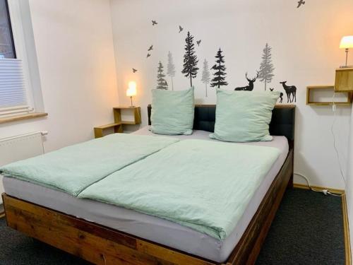 Forsthaus am Waldrand的卧室配有一张带绿床单和墙上树木的床。