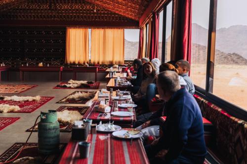 瓦迪拉姆Bedouin Nights Camp的一群人坐在长桌旁吃着食物