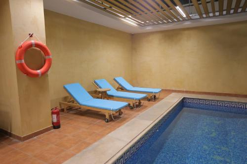 利雅德Dar Hashim Hotel Suites - Alnuzha的一个带蓝色椅子的游泳池,一个红色救生器