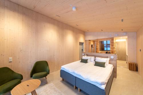 库奥皮奥Bella Lake Resort的一间卧室配有一张床和两张绿色椅子