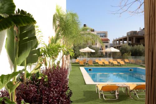 赫索尼索斯Sergios Hotel的庭院内的游泳池,配有椅子和遮阳伞
