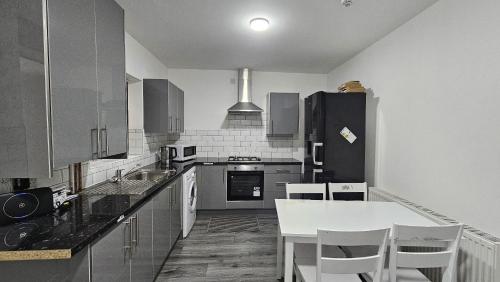 奥尔德伯里Spacious Double Bedroom with Private Toilet and Shared Kitchen with on premesis parking的厨房配有白色桌子和黑色冰箱。