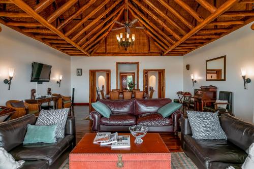 Katwe威亚野生山林小屋的客厅配有皮革家具和木制天花板