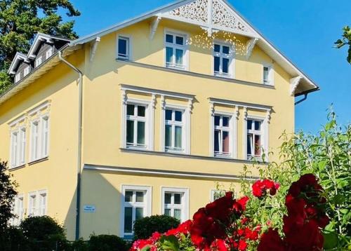 奥斯特巴德·哥伦Villa Granitz - Ferienwohnung 45466 (Sassnitz)的前面有红色花的黄色房子