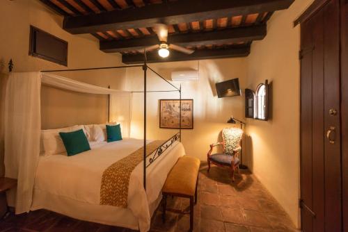 圣多明各埃尔比特里欧卡萨博物馆酒店的一间卧室,卧室内配有一张床和一把椅子
