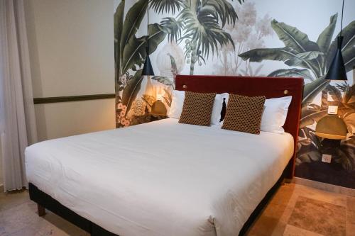 戛纳戛纳中心普鲁伊别墅酒店的卧室配有白色的床铺,墙上挂着植物