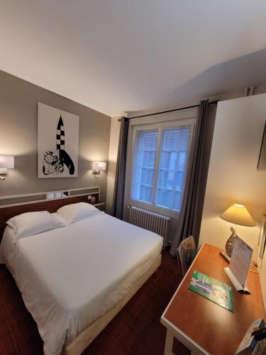 布鲁瓦Logis Hôtel Restaurant LE MONARQUE的酒店客房设有一张大床和一张桌子。