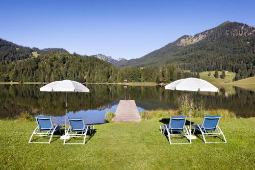 史毕辛吉Arabella Alpenhotel am Spitzingsee, a Tribute Portfolio Hotel的湖边的一组椅子和遮阳伞