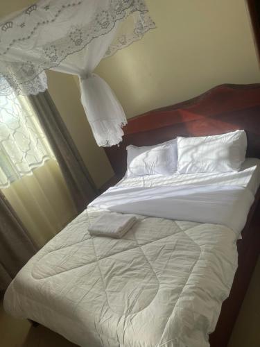 恩德培7 Days Hotel的一张带白色床单和枕头的床,靠窗