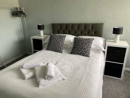 莫克姆Quiet Ground Floor apartment with parking的一张带枕头和毛巾的白色床