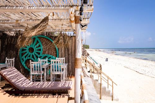 江比阿Pili Pili Sunrise的海滩上的餐厅,配有椅子和海洋