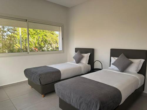 特马拉Residence Neya Harhoura的带窗户的客房内的两张床
