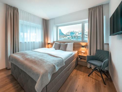 施利特尔斯AlpenLuxus' SIGIS Zillertalblick with 3 Bedrooms & Parking Space的卧室配有床、椅子和窗户。