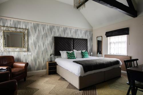 布罗肯赫斯特玫瑰和皇冠宾馆的一间卧室配有一张床、一把椅子和镜子